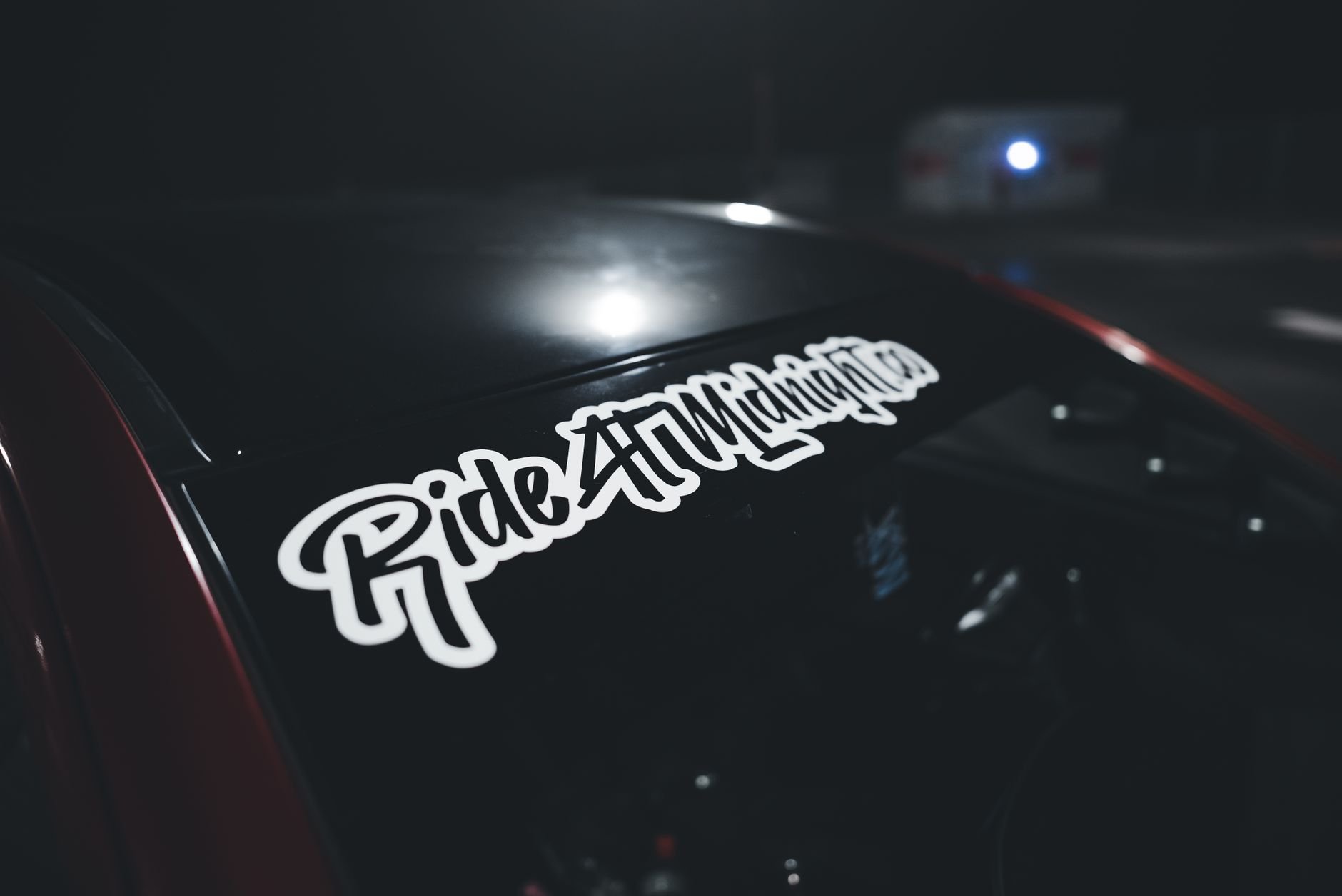 A close-up of a car windshield with a sticker in a dark setting.